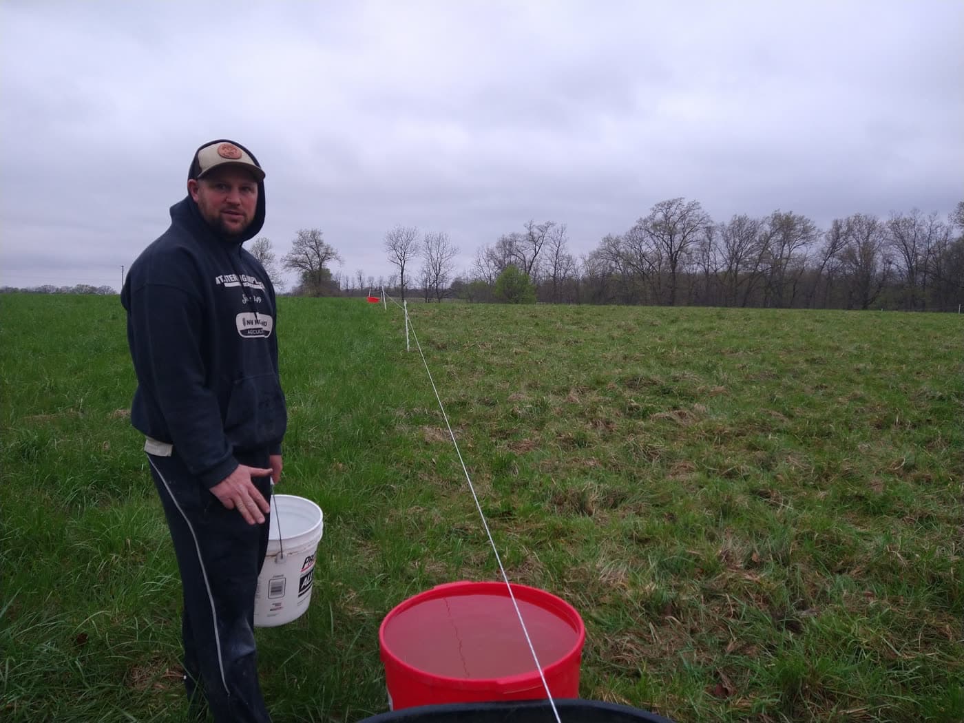 Kyle Leonard standing along a fence line in a green pasture